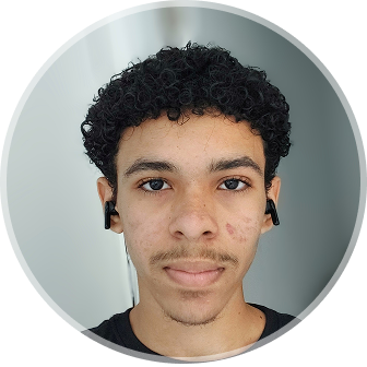 Foto de Alisson com gesto profissional,camisa preta, fone de ouvido e fundo borrado 